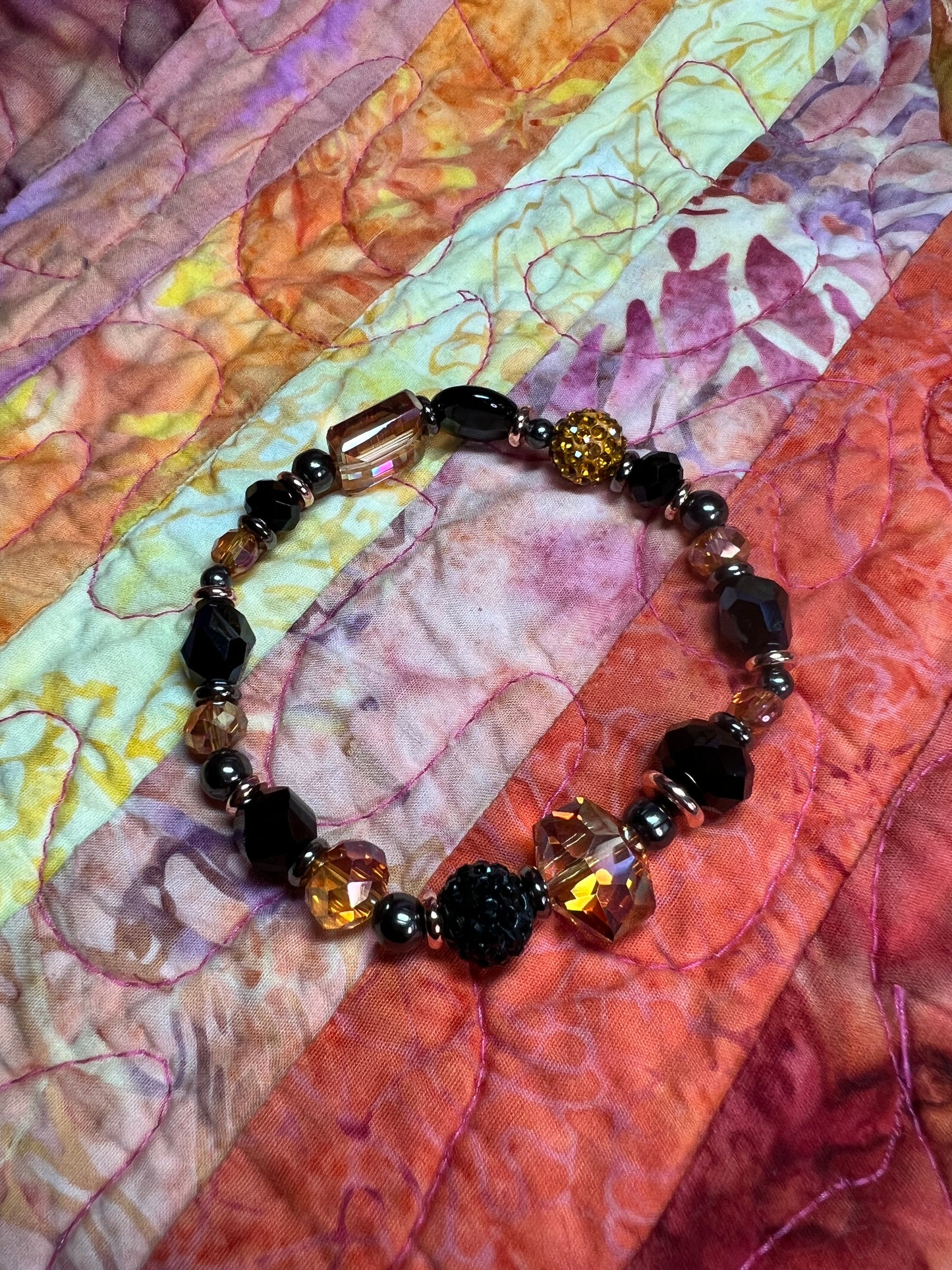 Bracelet- Opaque black crystal, gunmetal & copper plated metal beads, & iridescent orange crystals.