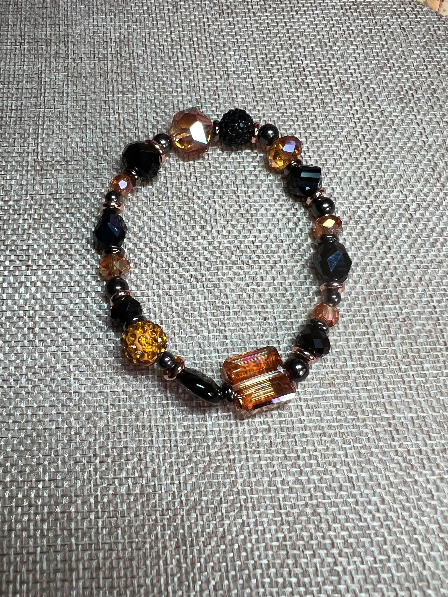 Bracelet- Opaque black crystal, gunmetal & copper plated metal beads, & iridescent orange crystals.