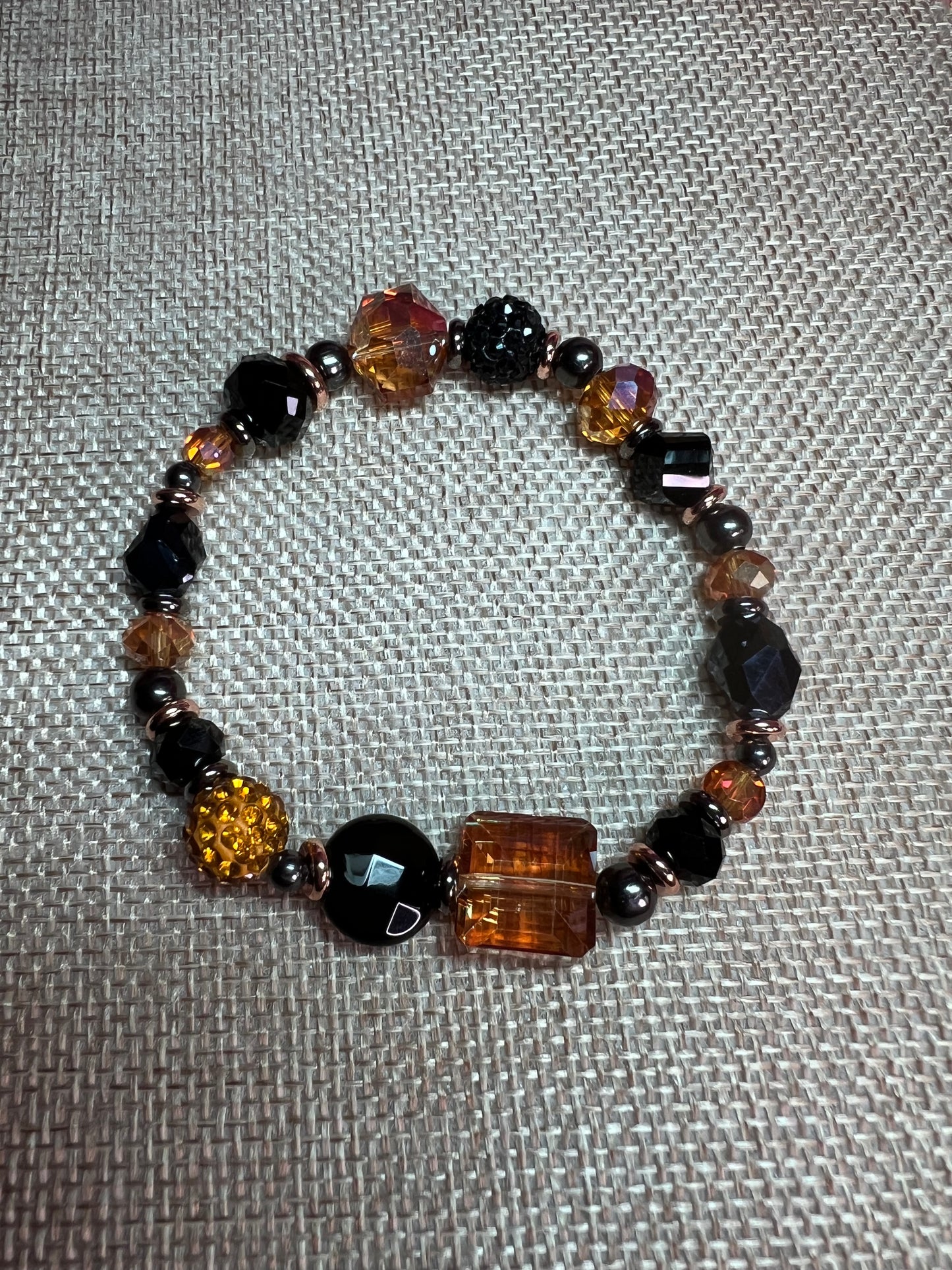 Bracelet- Opaque black crystal, gunmetal & copper plated metal beads, & iridescent orange crystals.