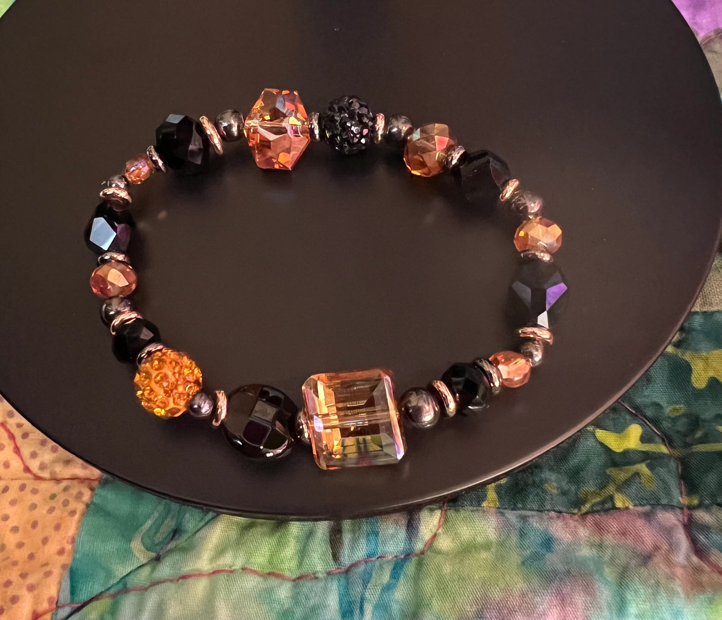 Bracelet- Opaque black crystal, gunmetal & copper plated metal beads, & iridescent orange crystals.