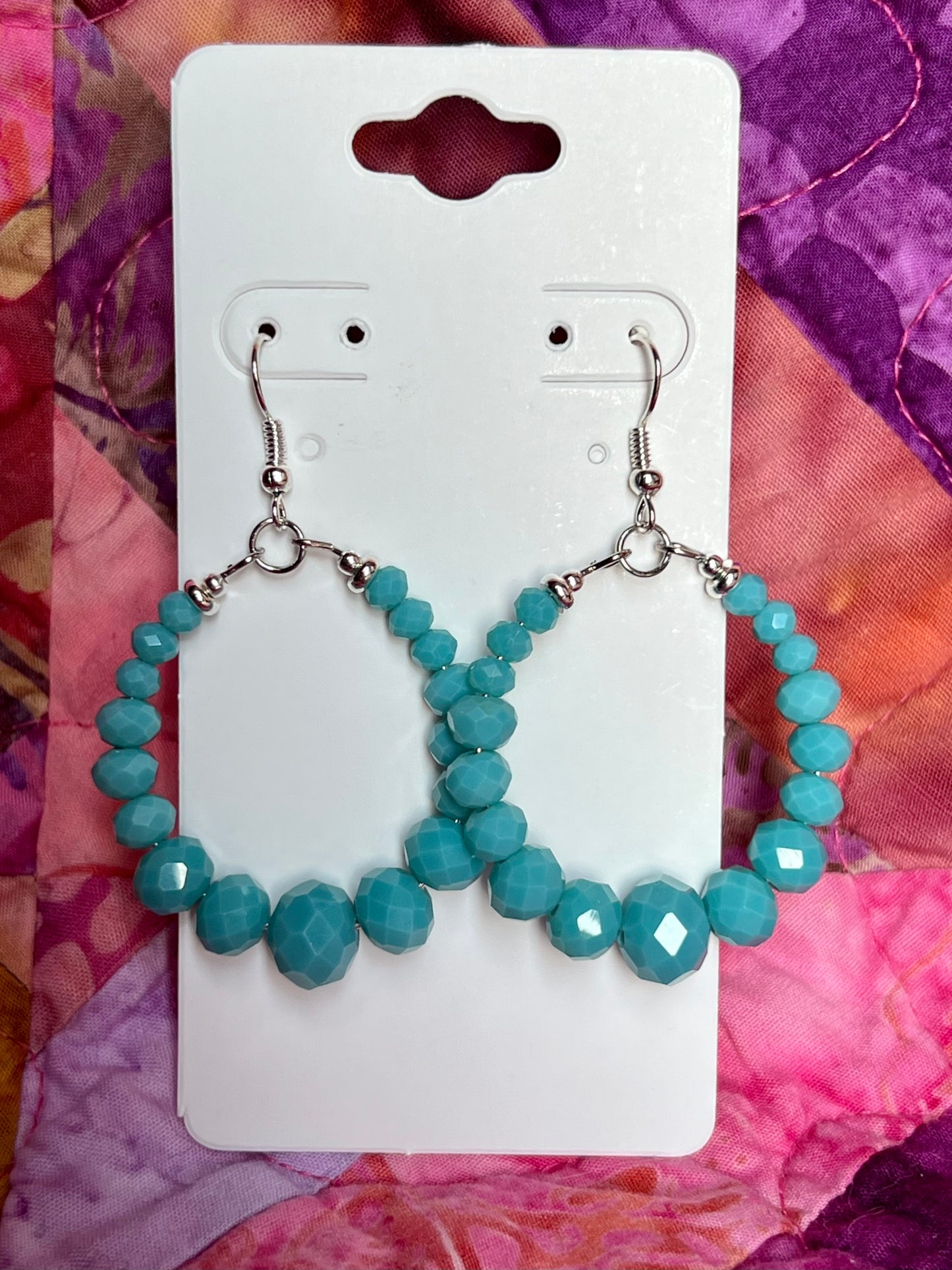 Earrings- Silver plated metal hoops with opaque turquoise colored crystals.