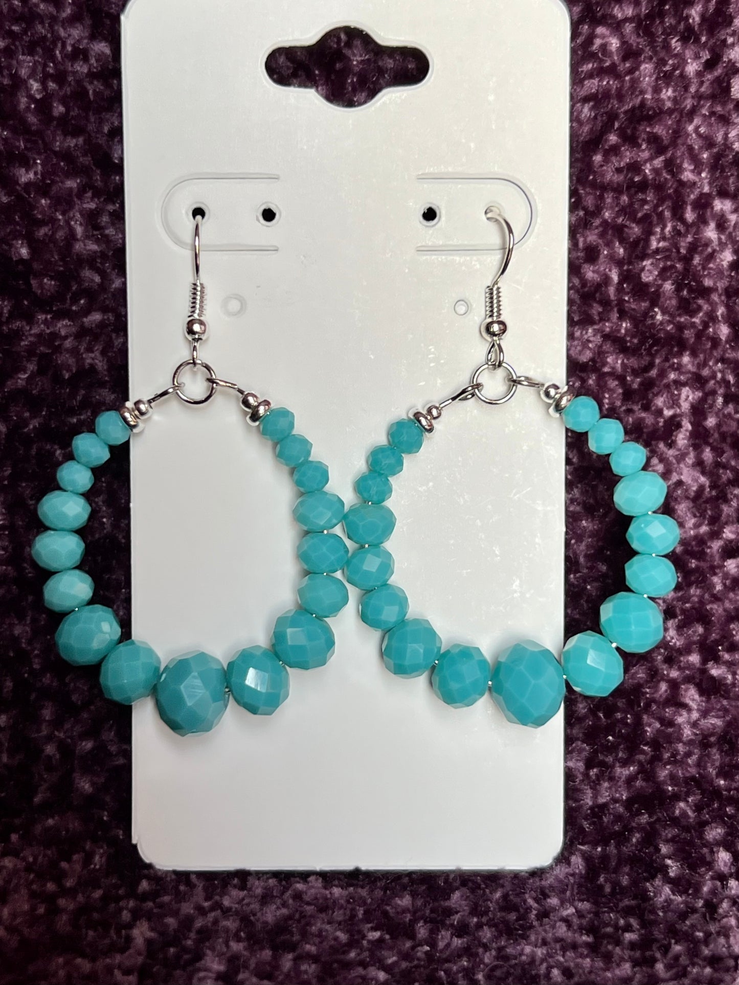 Earrings- Silver plated metal hoops with opaque turquoise colored crystals.