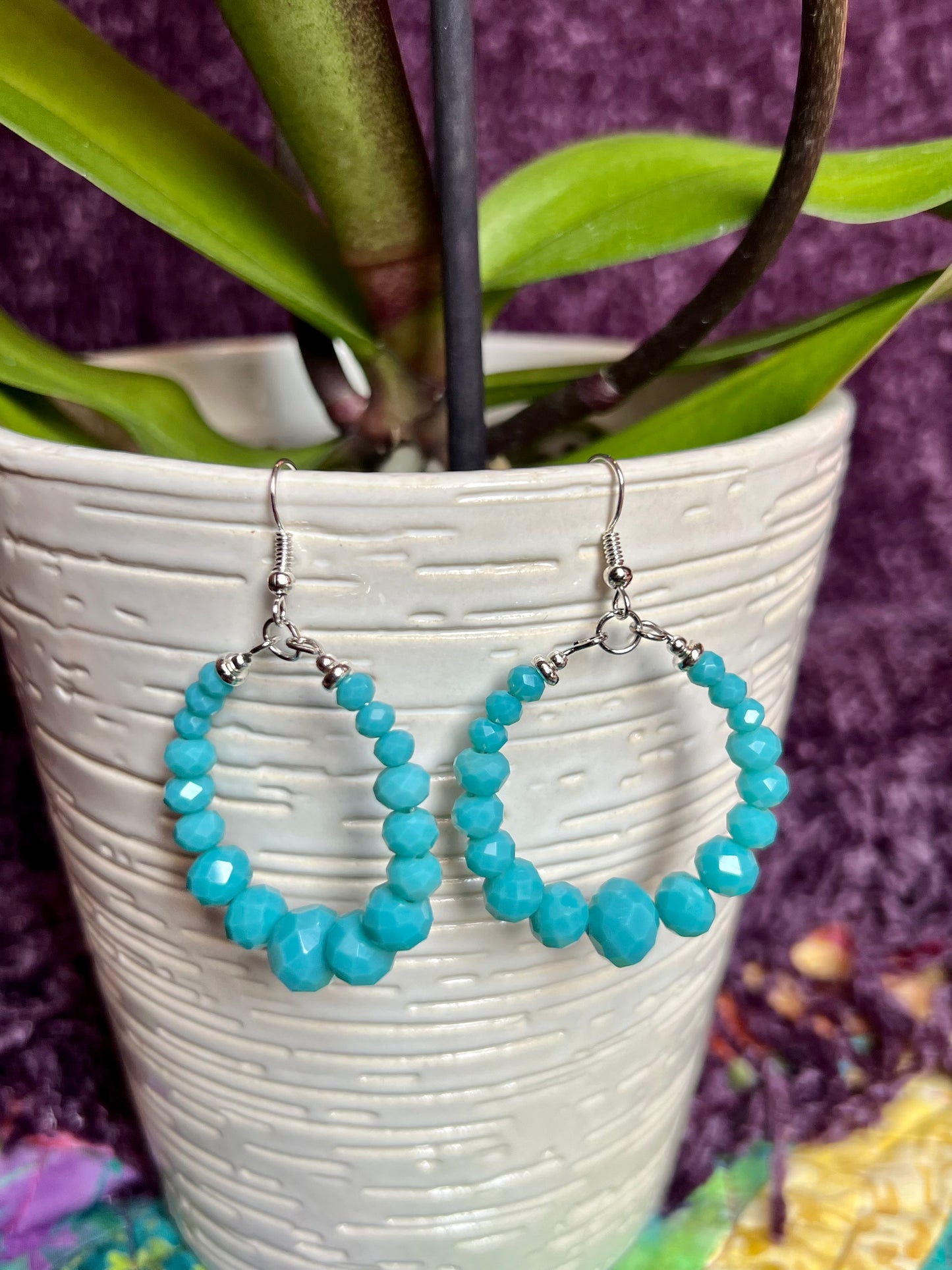 Earrings- Silver plated metal hoops with opaque turquoise colored crystals.
