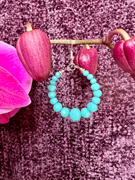 Earrings- Silver plated metal hoops with opaque turquoise colored crystals.