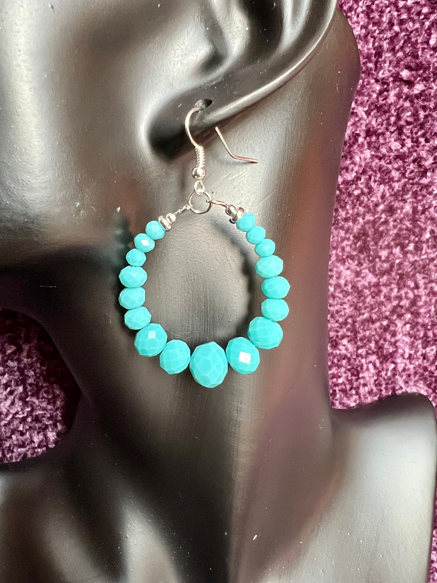 Earrings- Silver plated metal hoops with opaque turquoise colored crystals.