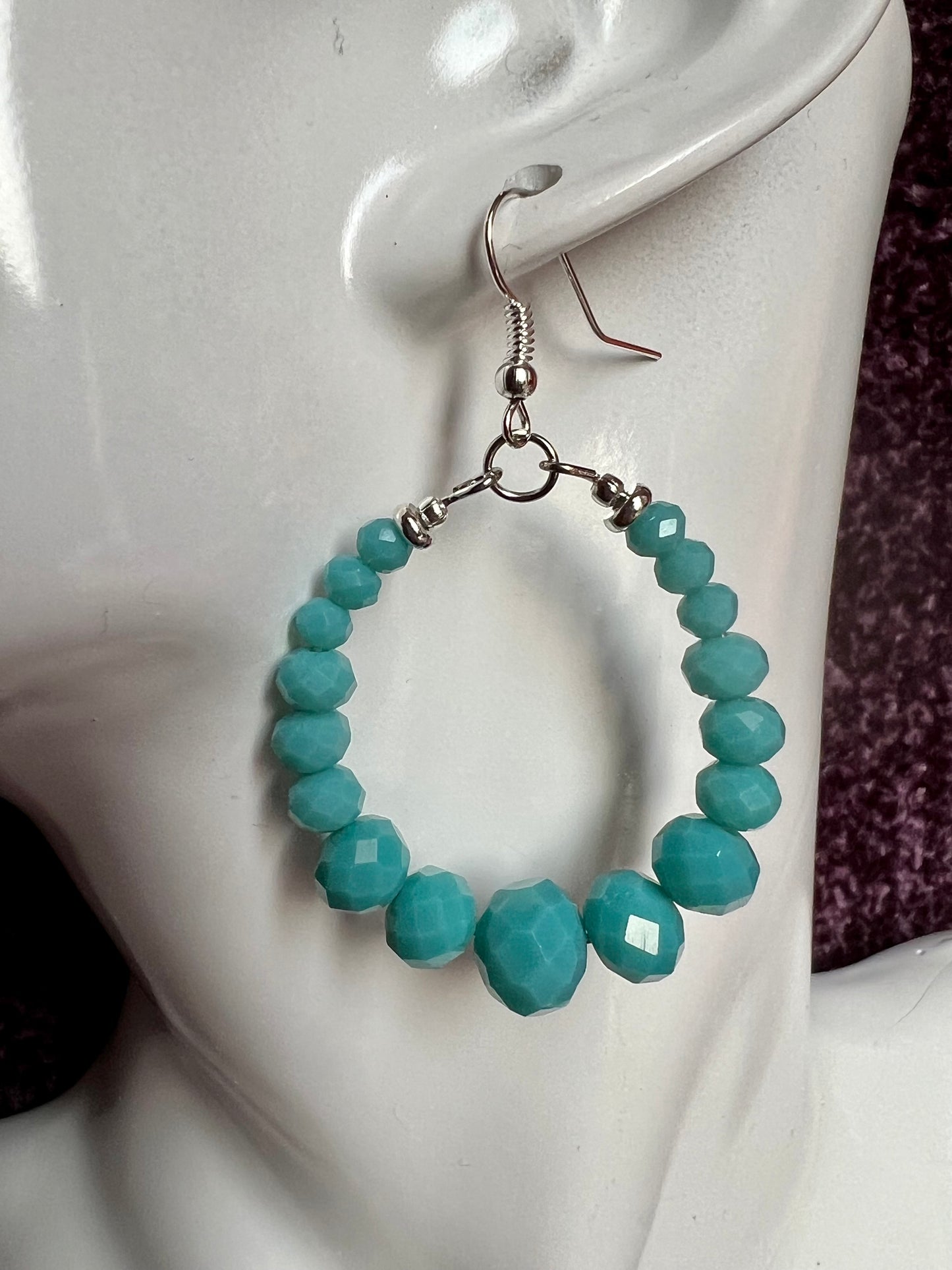 Earrings- Silver plated metal hoops with opaque turquoise colored crystals.