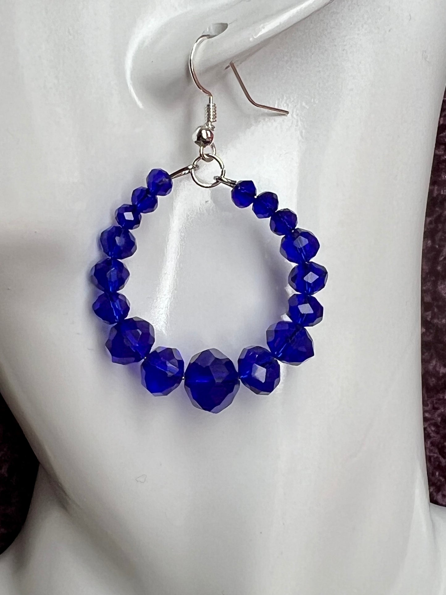 Earrings- Silver plated metal hoops with blue crystals.