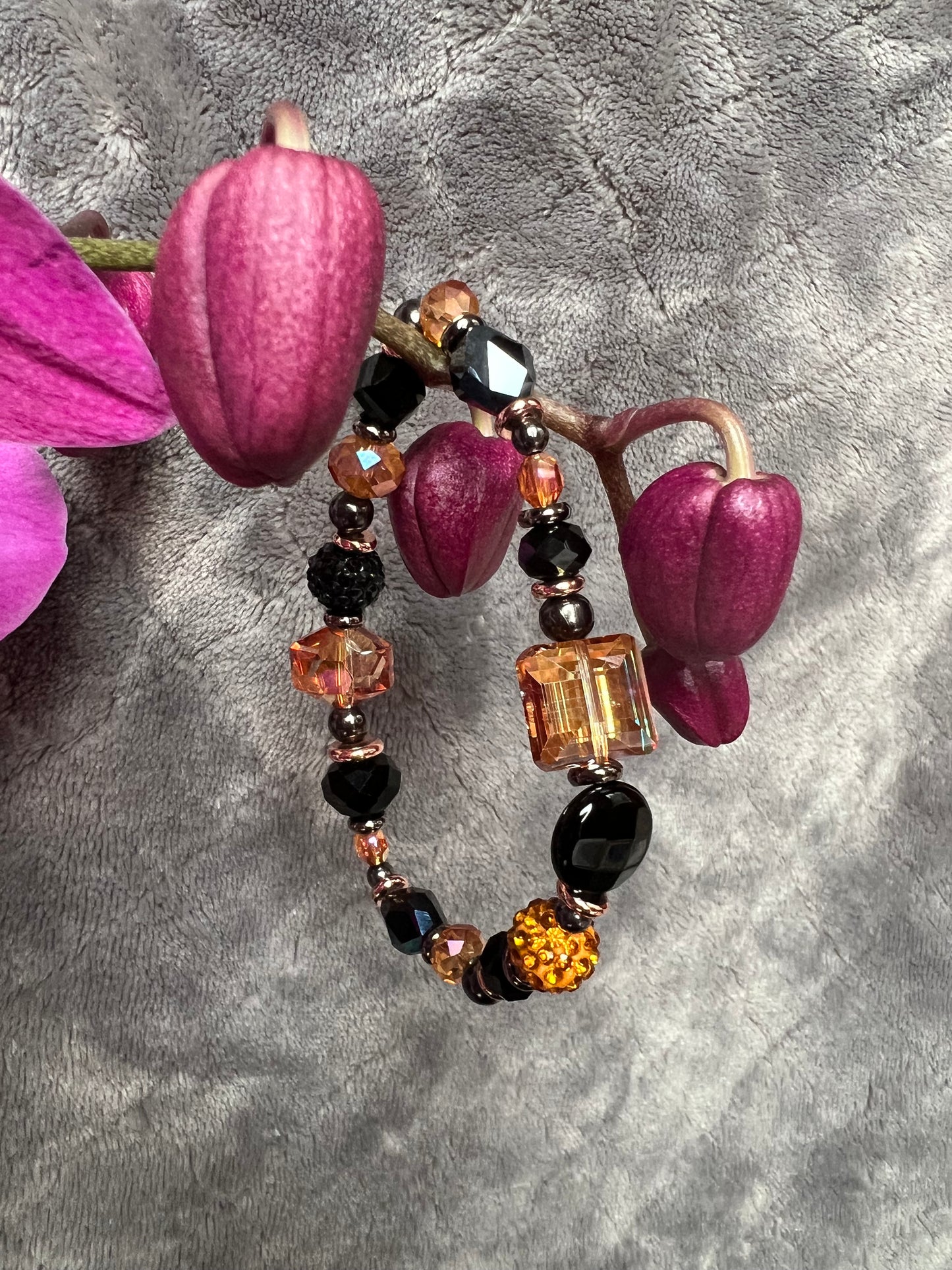 Bracelet- Opaque black crystal, gunmetal & copper plated metal beads, & iridescent orange crystals.