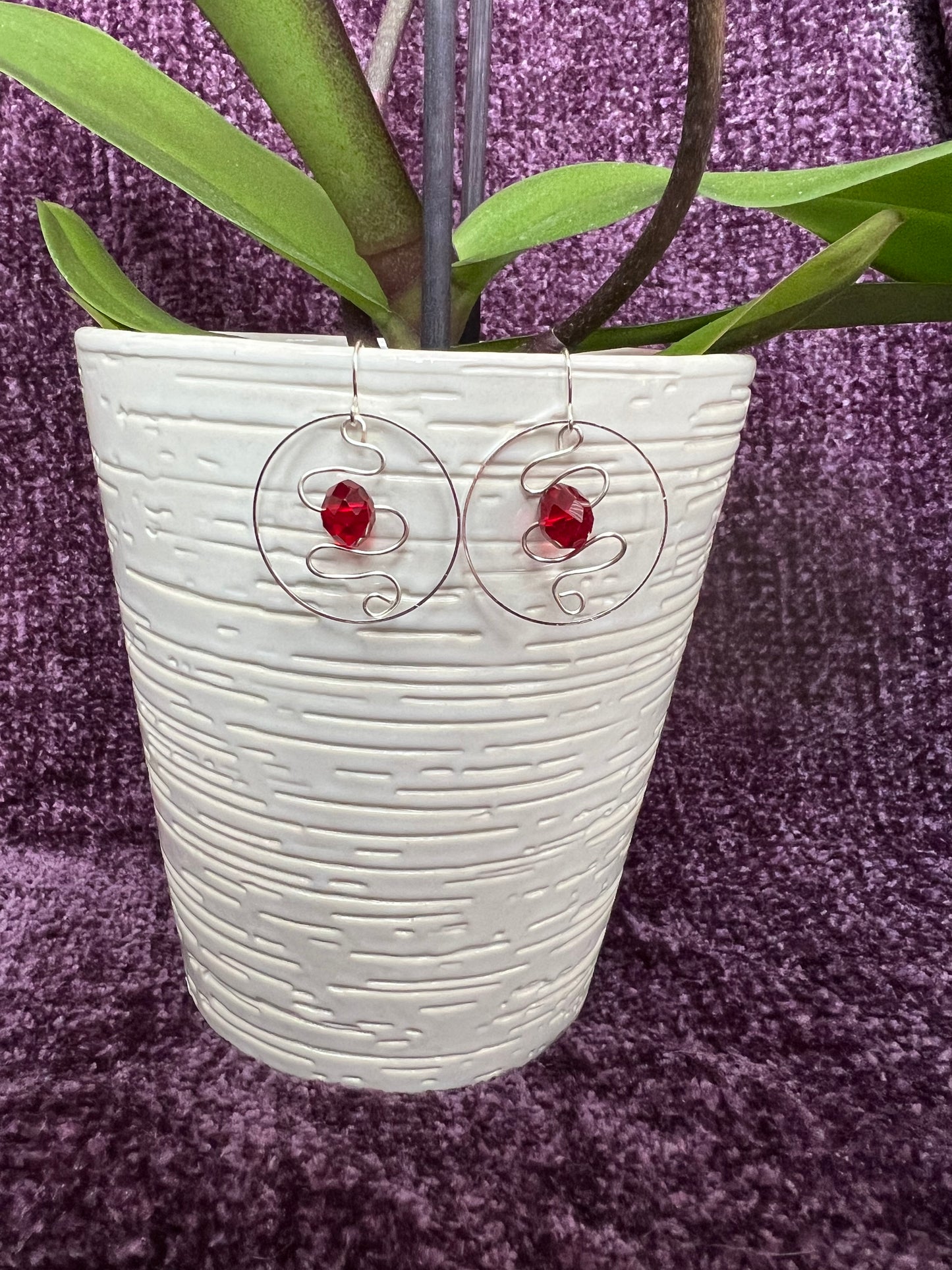 Earrings- Silver plated hoop with wire scroll design and red crystal.