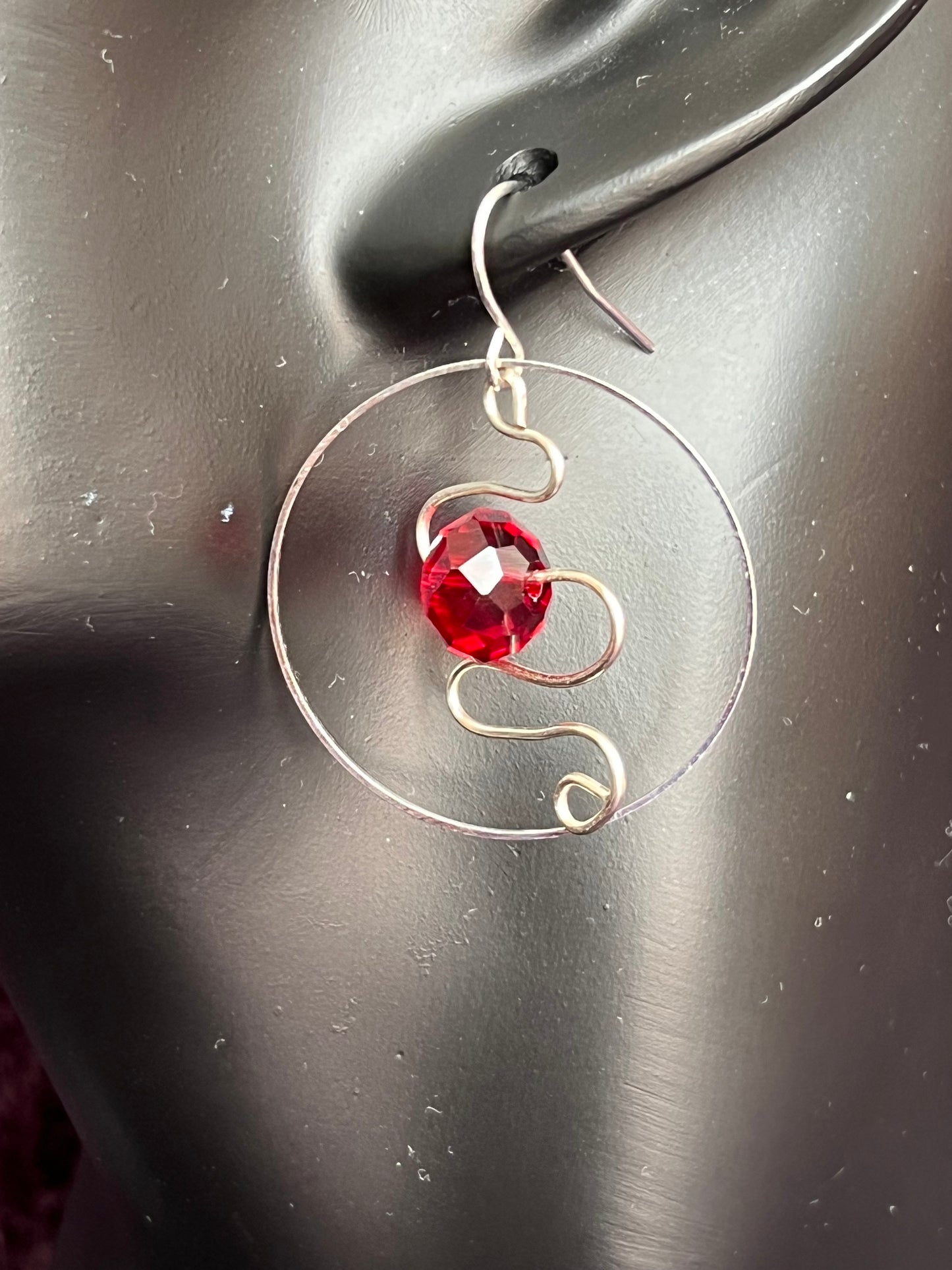 Earrings- Silver plated hoop with wire scroll design and red crystal.