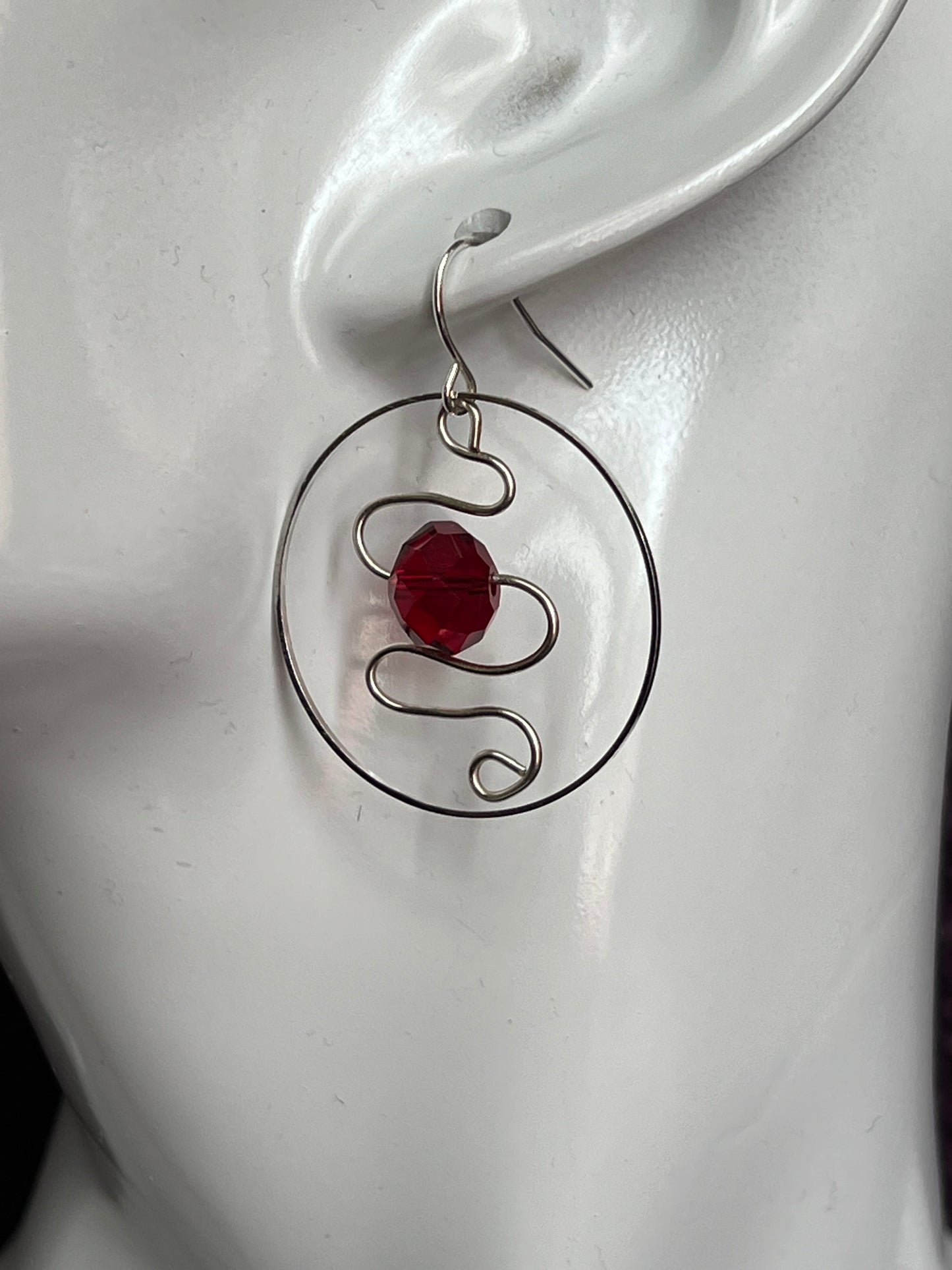 Earrings- Silver plated hoop with wire scroll design and red crystal.