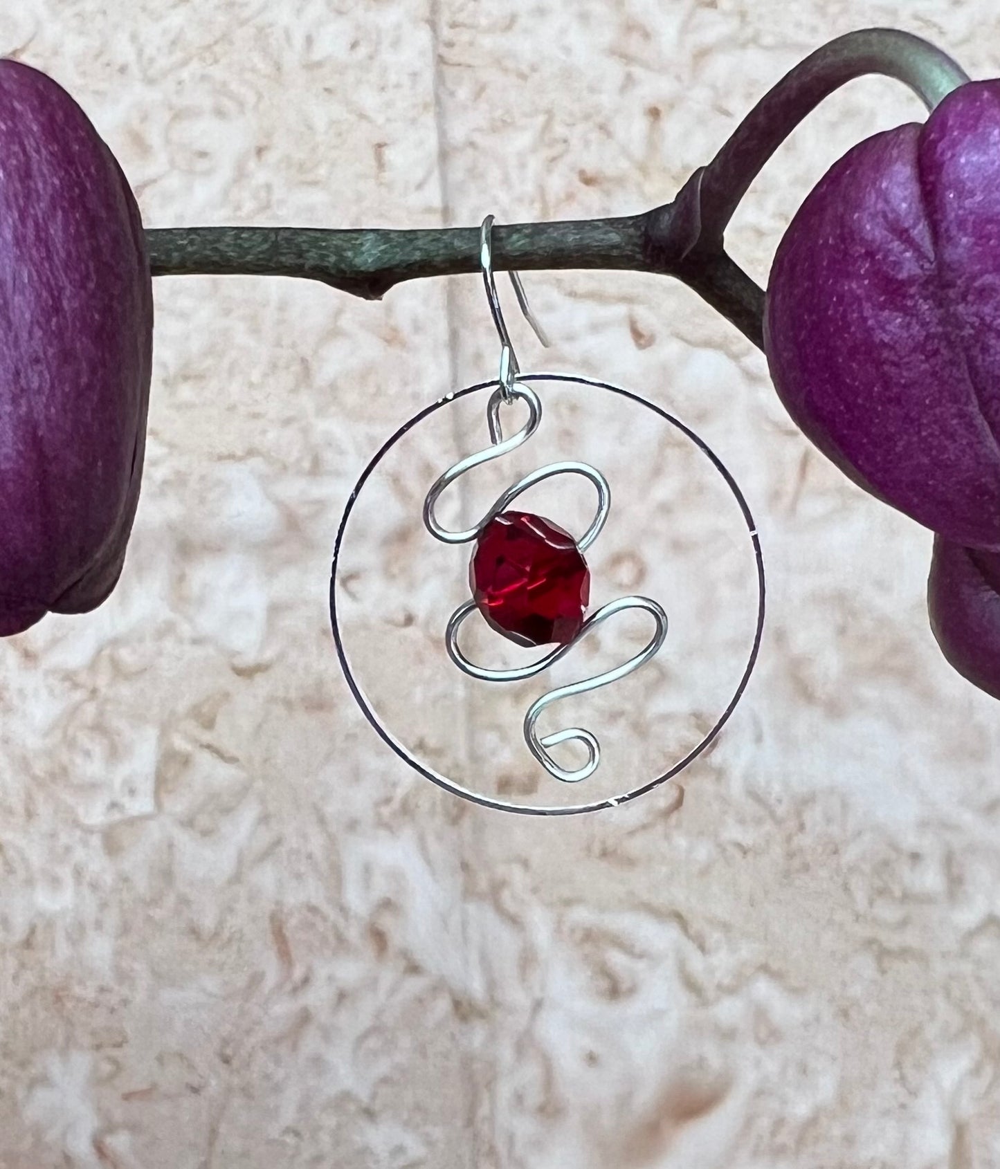 Earrings- Silver plated hoop with wire scroll design and red crystal.