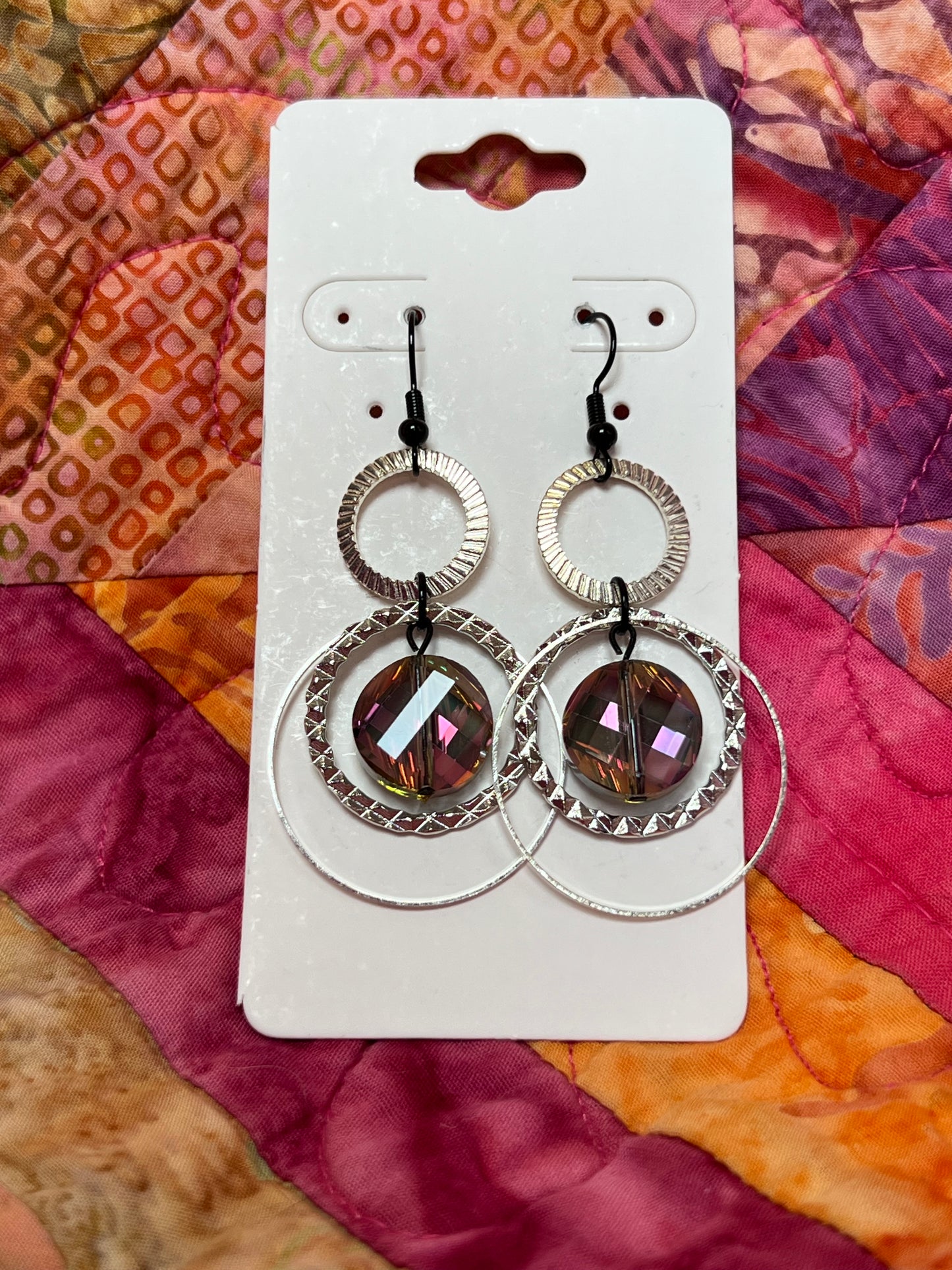 Earrings- Silver plated metal hoops and black plated wires with iridescent coin crystals.