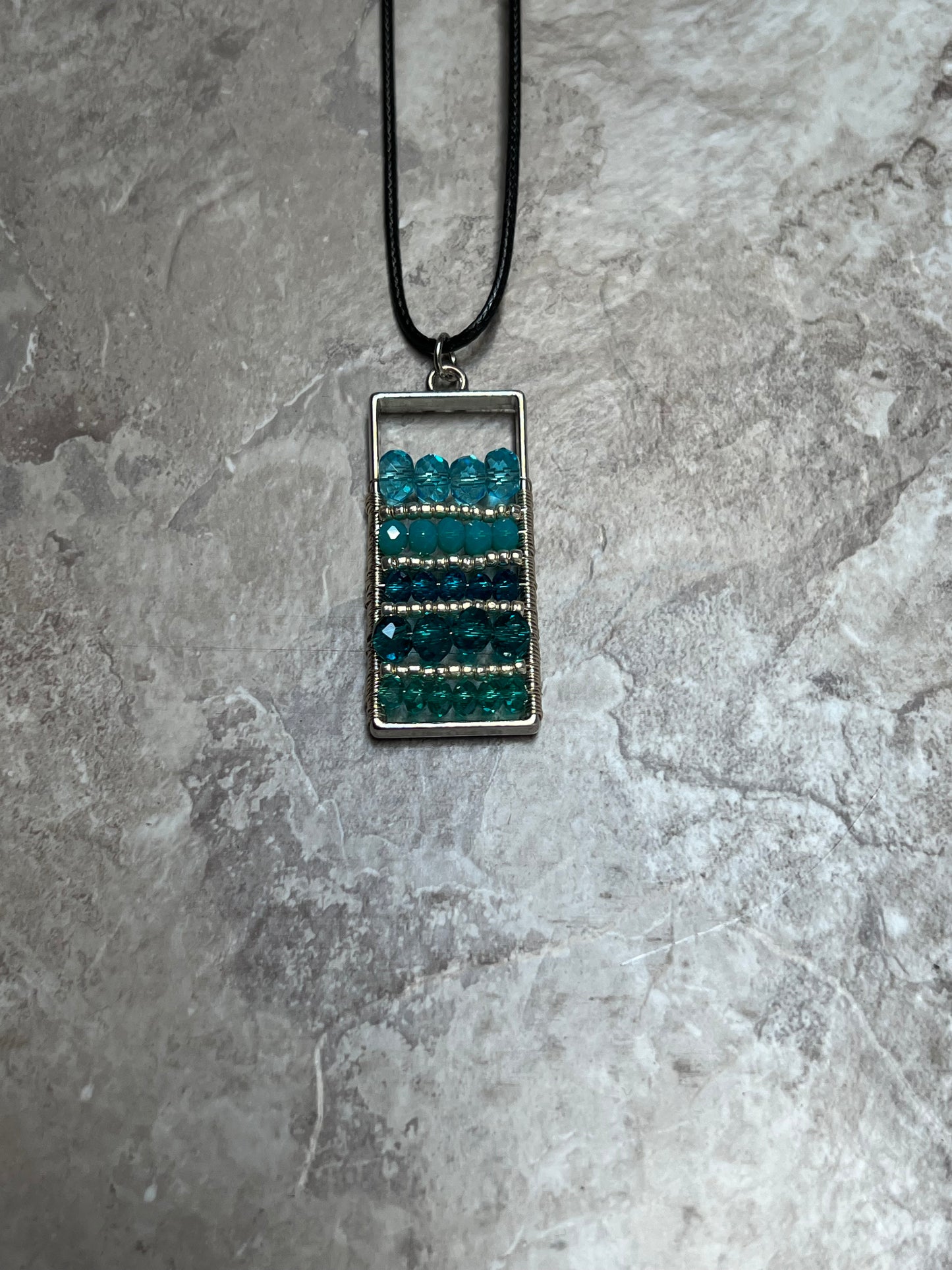 Necklace- Waxed cotton cord with silver plated metal and clasp with various shades of turquoise colored crystals.