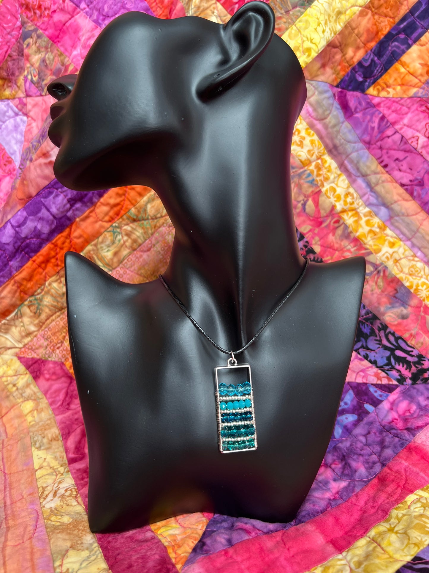 Necklace- Waxed cotton cord with silver plated metal and clasp with various shades of turquoise colored crystals.