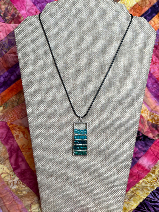 Necklace- Waxed cotton cord with silver plated metal and clasp with various shades of turquoise colored crystals.