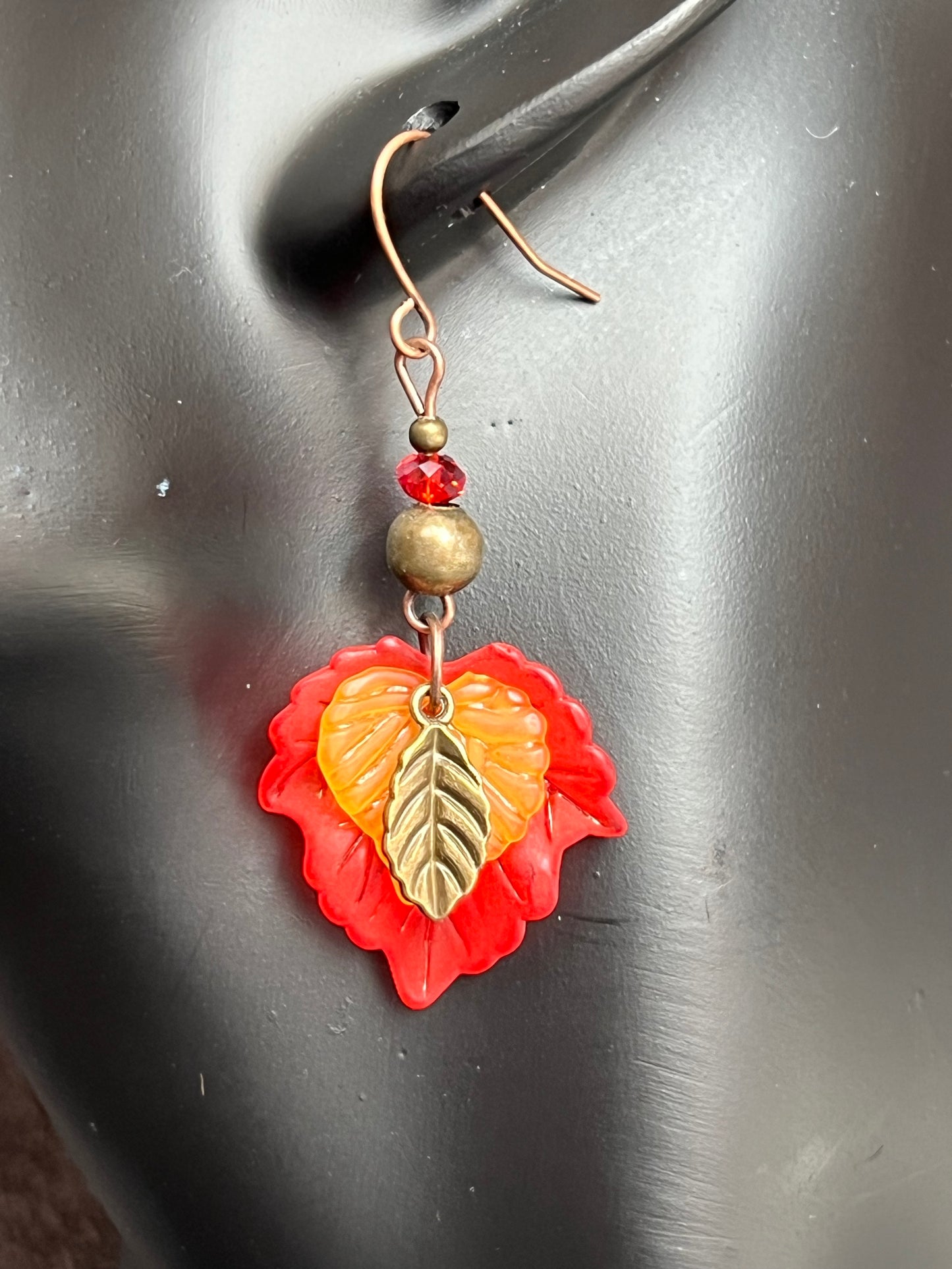 Earrings- Antique copper plated ear wires, antique gold leaf charms, red and orange lucite leaves.