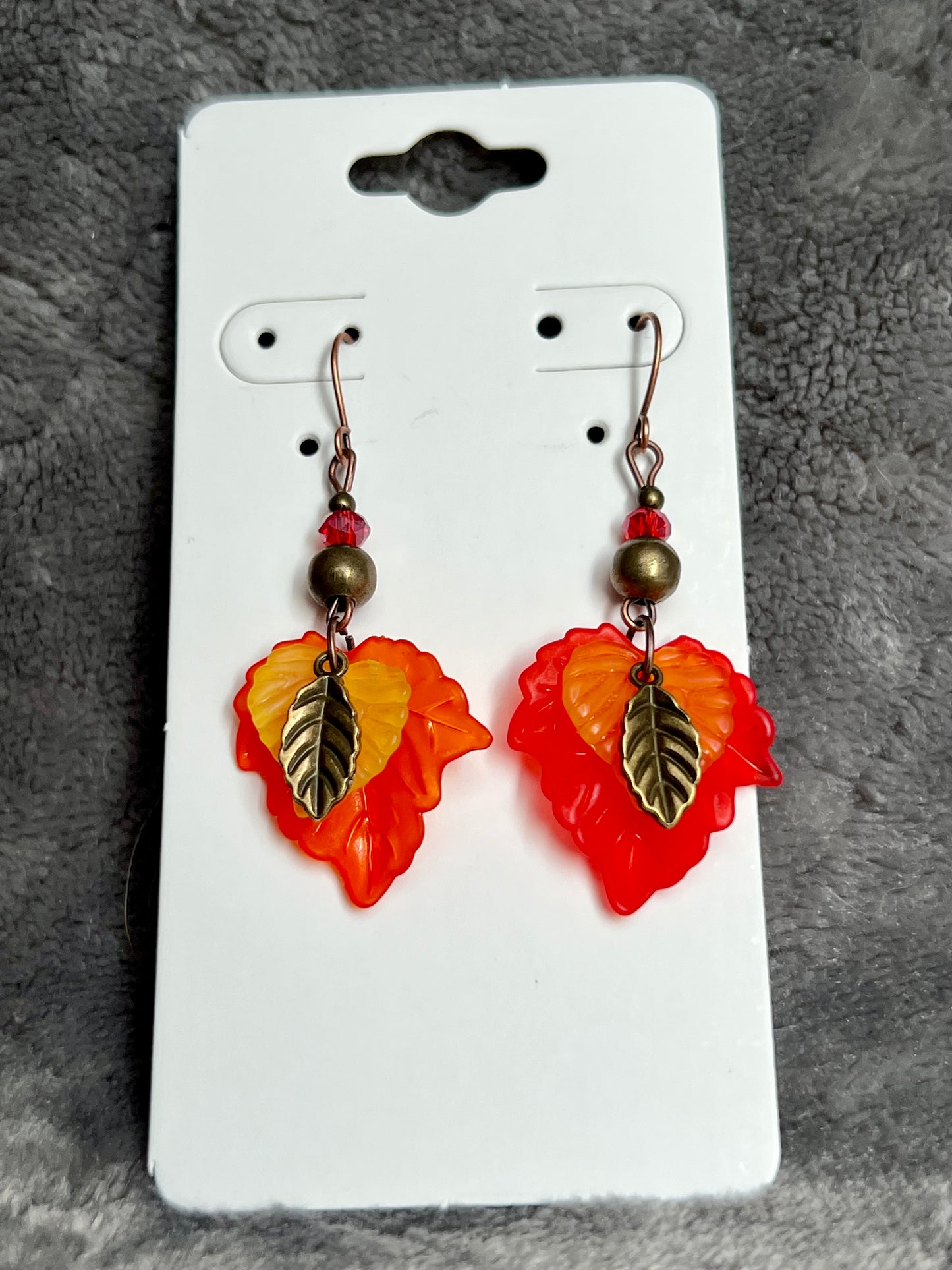 Earrings- Antique copper plated ear wires, antique gold leaf charms, red and orange lucite leaves.