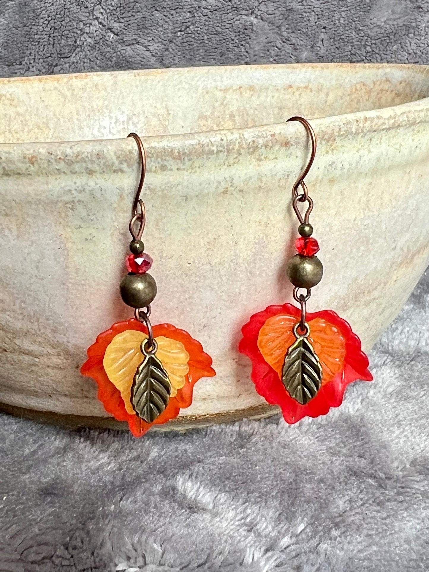 Earrings- Antique copper plated ear wires, antique gold leaf charms, red and orange lucite leaves.