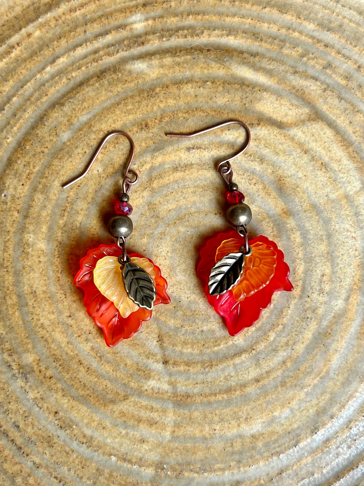 Earrings- Antique copper plated ear wires, antique gold leaf charms, red and orange lucite leaves.